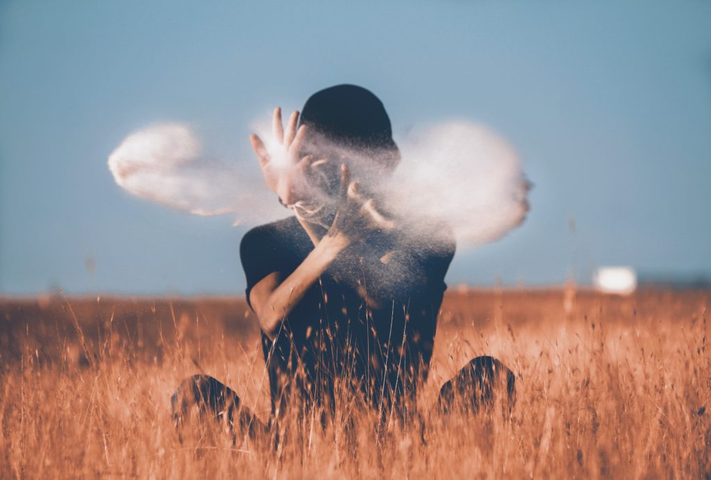 A boy in a farm with dust around his hands.