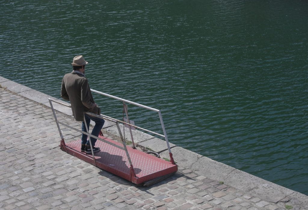 A man standing near water thinking.