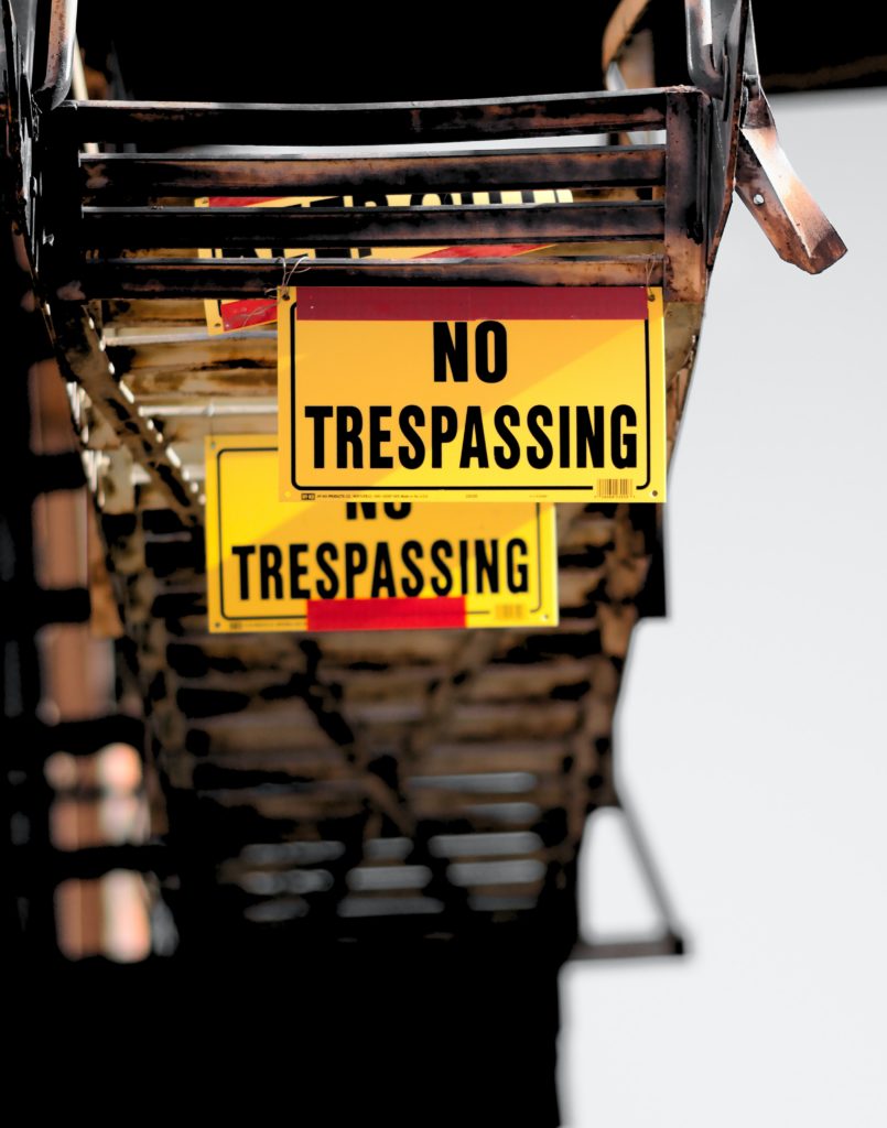 An image of a sign board on which "No Trespassing" has been written